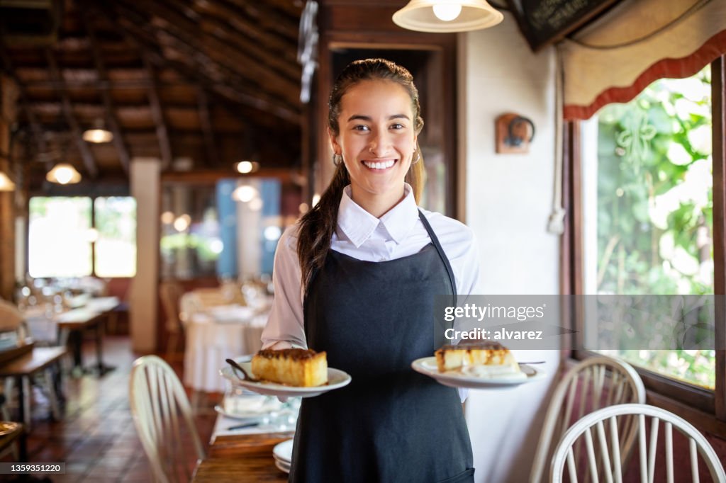 Lächelnde Kellnerin serviert Dessert im Restaurant