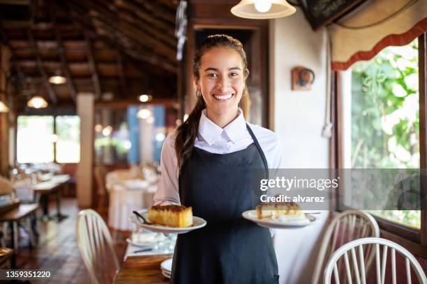 lächelnde kellnerin serviert dessert im restaurant - woman holding cake stock-fotos und bilder