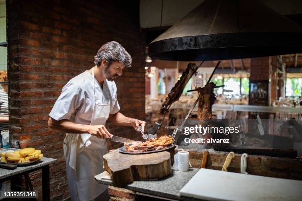 professional chef cooking meat in a restaurant kitchen - argentina food imagens e fotografias de stock