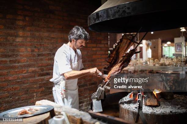professional cook working in a restaurant roasting meat over the coal fire - pork cuts stock pictures, royalty-free photos & images