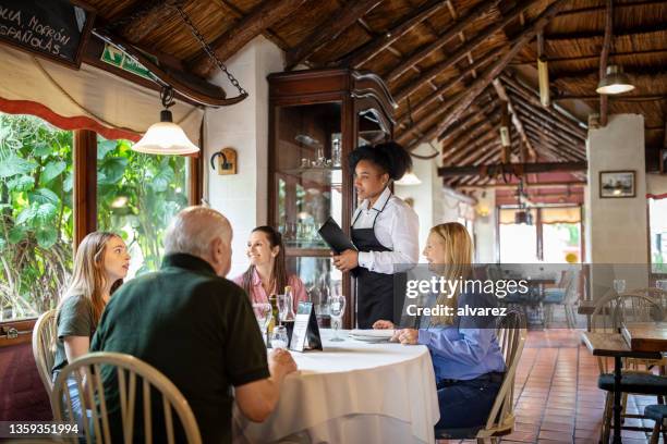 waitress taking order from a family sitting at a restaurant table - family ordering at restaurant stock pictures, royalty-free photos & images