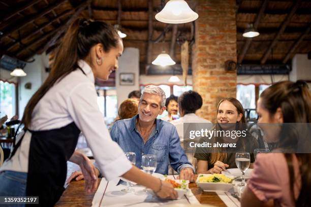 waitress serving food to family at restaurant - family dining stockfoto's en -beelden