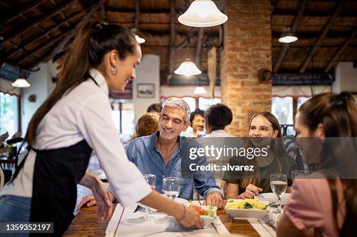 Garçonete De Restaurante Servindo Mesa Com Comida Imagem de Stock