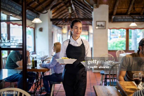 kellnerin serviert essen im restaurant - portion stock-fotos und bilder