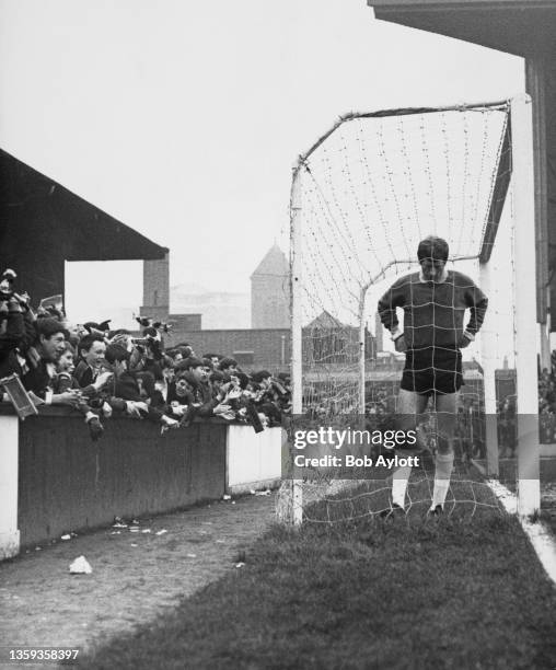 Fans look on as Jim Standen, Goalkeeper for West Ham United Football Club stands inside his goal during the English League Division One game against...