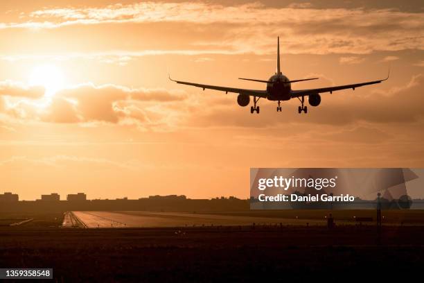 airplane landing at sunset, sunsets background, travel background - land speed stockfoto's en -beelden