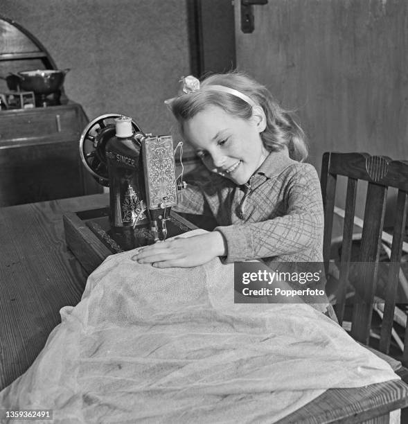 British child entertainer Petula Clark uses a Singer sewing machine to alter one of her frocks at home in Chessington, Surrey, England during World...