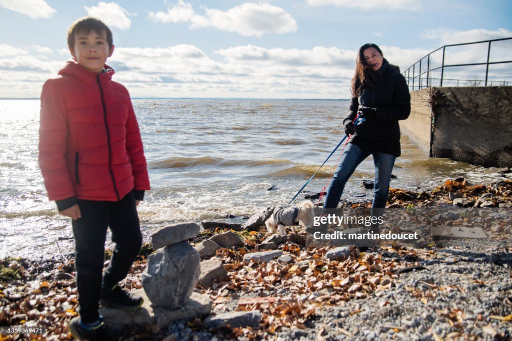 Mother and son walking the dogs on lake side in autumn.