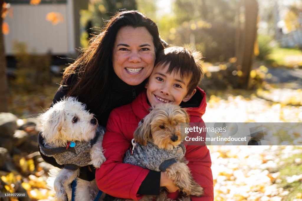 Mother and son family portrait with dogs in autumn leaves.