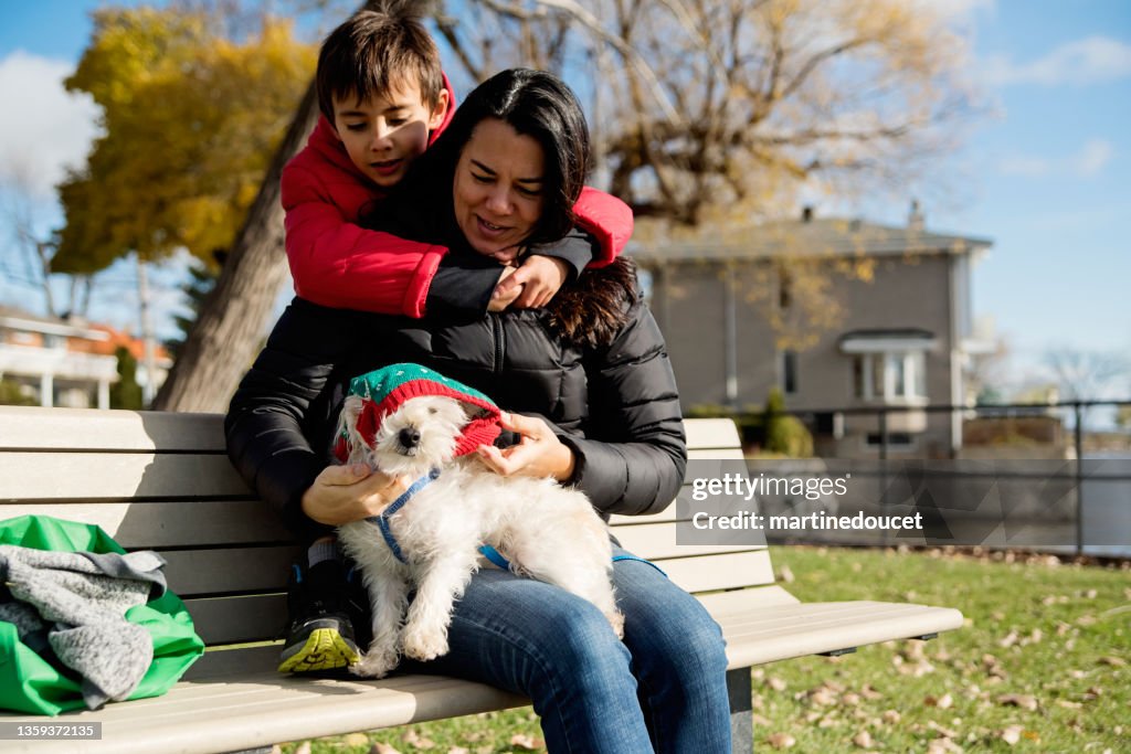 Mother and son family changing dog outfit on a bench.