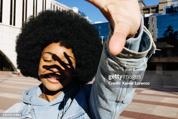 young african woman covering herself from the sunlight with her hand out - obscured face stock-fotos und bilder