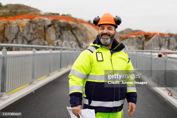 portrait of male engineer in reflecting clothing standing on bridge - albañil fotografías e imágenes de stock