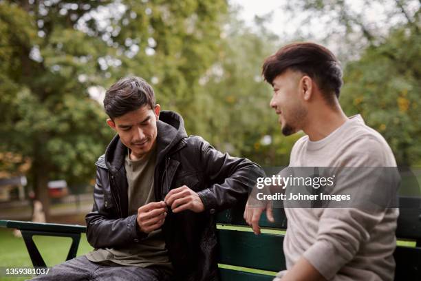 men sitting on bench and talking - chatting park stockfoto's en -beelden