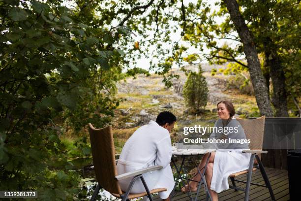 couple in bathrobes sitting on deck - robe stock pictures, royalty-free photos & images