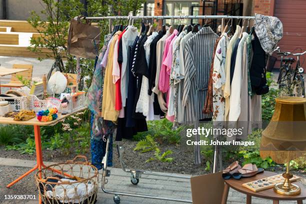 clothes in rack at yard sale - rommelmarkt stockfoto's en -beelden
