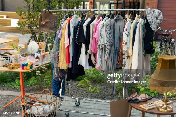 clothes in rack at yard sale - flea market stockfoto's en -beelden