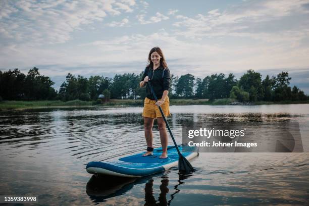 woman paddleboarding, boats inn background - paddleboard stock pictures, royalty-free photos & images