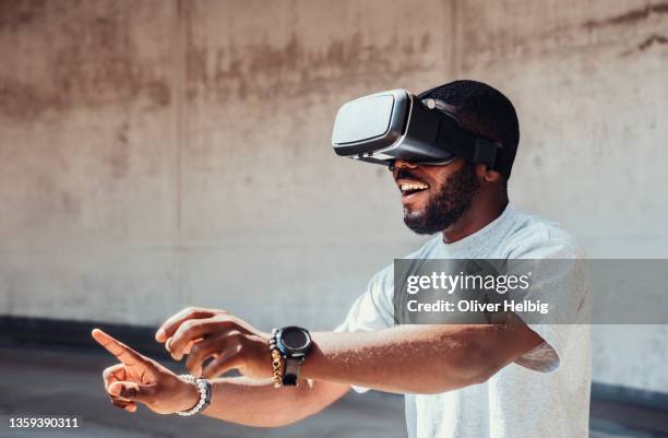 young african american man uses virtual reality glasses and has fun with it - 3d hand stock-fotos und bilder