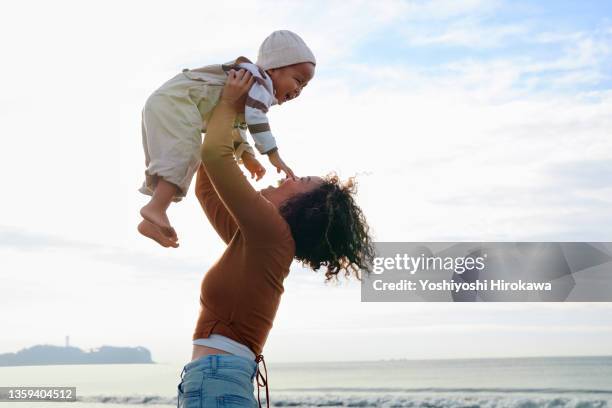 mother lifts smiling son high - always with a smile stock pictures, royalty-free photos & images