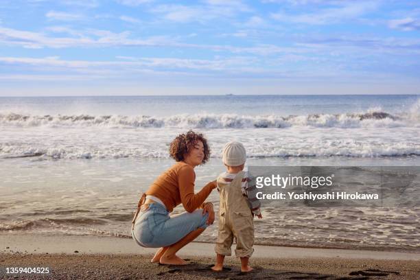 genuine mother showing her son the sea - asian young family stock-fotos und bilder