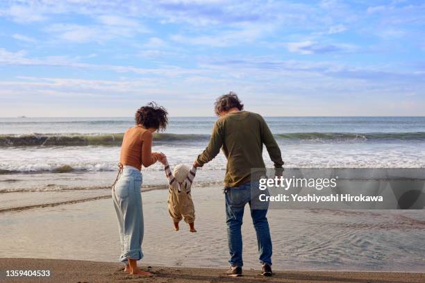 family walking along beach - jeune famille photos et images de collection