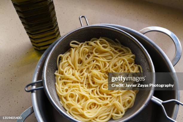 boiled spaghetti in colander - spaghetti stock-fotos und bilder