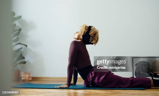 beautiful woman in a cobra pose doing yoga at home - cobra stretch stock pictures, royalty-free photos & images