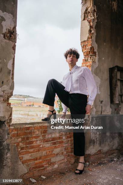 gender fluid young man in high heels in a vintage dress in a abandoned building - high heels stock-fotos und bilder