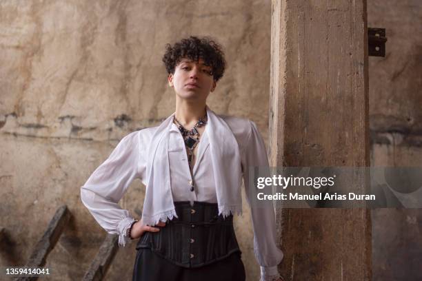 portrait of a boy with curly transgender hair, looking at the camera in an abandoned factory. - artists model stock-fotos und bilder