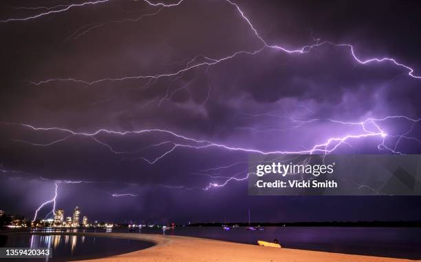 flashes of bright lightning strikes across the water with stormy clouds and sky - heat v thunder stock-fotos und bilder