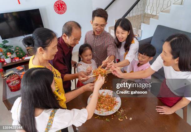 multi generation family celebrates chinesenew year with a prosperity toss or yee sang - shared prosperity stock pictures, royalty-free photos & images