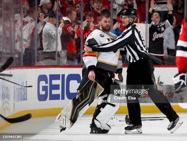 Robin Lehner of the Vegas Golden Knights is escorted off the ice after an altercation with members of the New Jersey Devils during the third period...