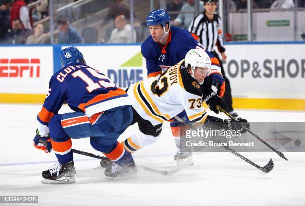 Cal Clutterbuck and Matt Martin of the New York Islanders combine to take down Charlie McAvoy of the Boston Bruins during the third period at the UBS...