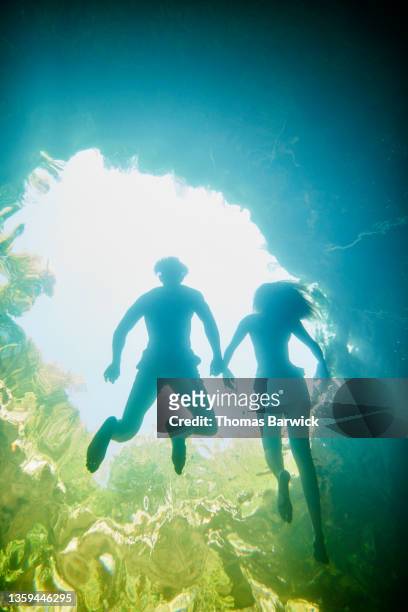 Wide shot underwater view of couple floating on their backs while swimming in cenote