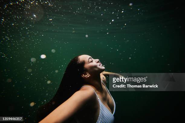 medium wide shot underwater view of woman swimming underwater in cenote - personal appearance stock pictures, royalty-free photos & images