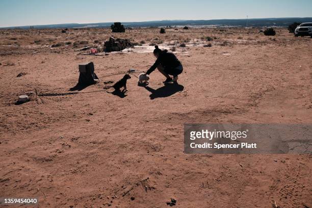 Carleena Chavez pets a dog outside of her home, which doesn't have running water on the Navajo Nation on December 16, 2021 in Thoreau, New Mexico....