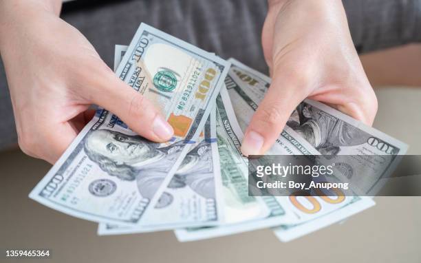 close up of someone hands holding and counting american dollar banknotes in her hand. - amerikaanse dollar stockfoto's en -beelden