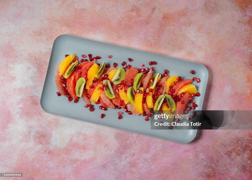 Tropical fruit salad on a tray on pink background