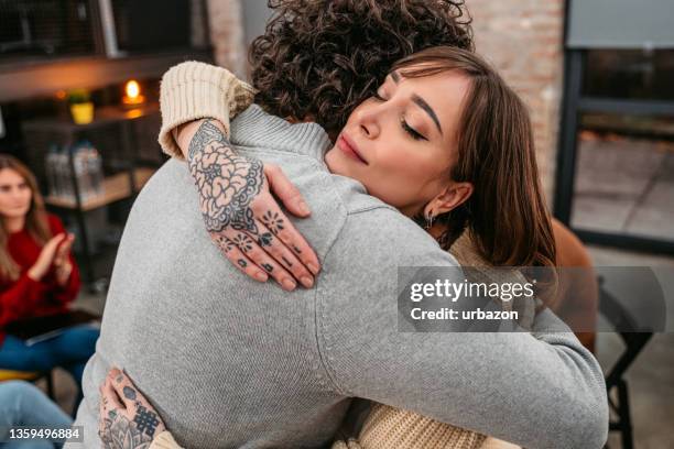 unterstützungsgruppenpatienten umarmen sich während der therapiesitzung - empathie stock-fotos und bilder