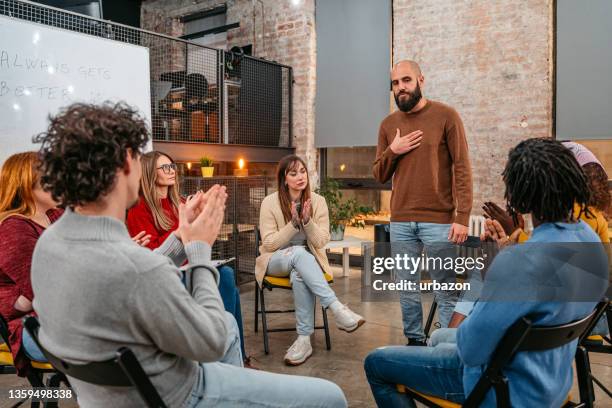 man talking to the other members of the therapy group - drogados imagens e fotografias de stock