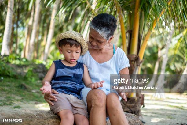 grandmother bonds with grandson on the beach - philippines family stock pictures, royalty-free photos & images