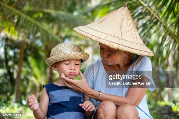 grandmother sits with grandson on the beach - philippines family 個照片及圖片檔