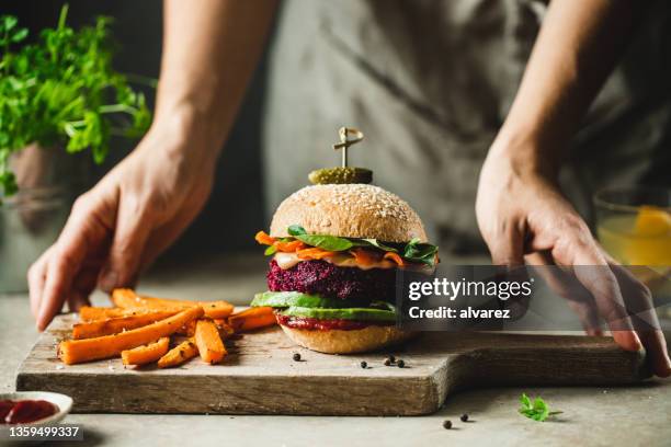 frau serviert ein köstliches veganes essensgericht - vegetarisch stock-fotos und bilder