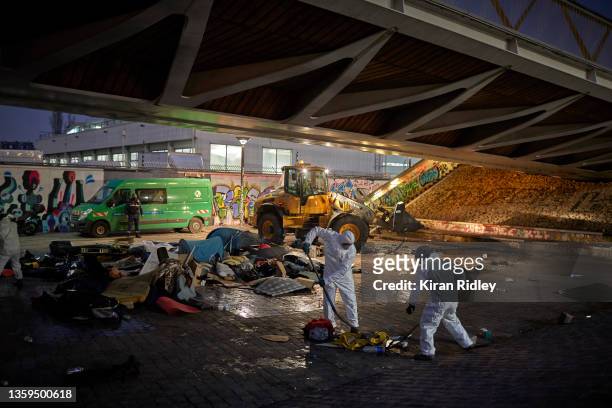 Paris municipal workers clear a makeshift migrant camp on the outskirts of Paris at dawn on December 17, 2021 in Paris, France. The camp of around...