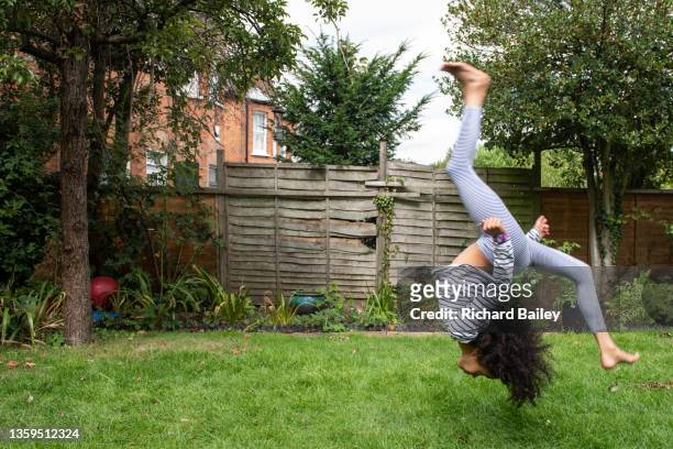 young girl performing gymnastics in the back garden - tumbling gymnastics stock pictures, royalty-free photos & images