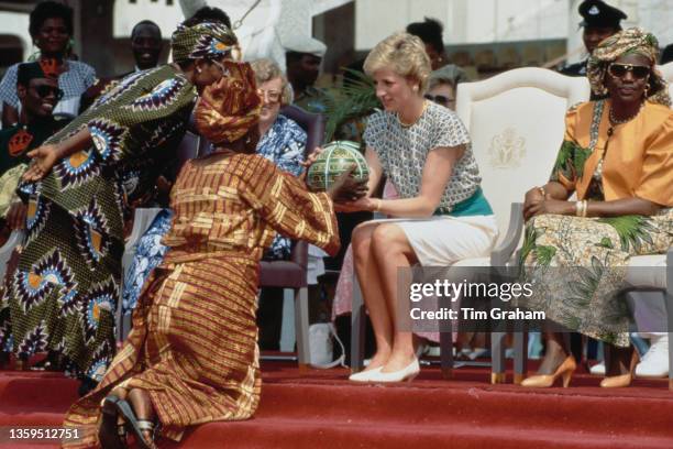 British Royal Diana, Princess of Wales , wearing an Alistair Blair dress, presented with a gift as she sits beside Maryam Babangida, the wife of the...