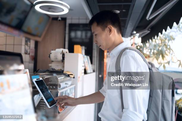 asian man is using facial recognition for payment - biométrie photos et images de collection