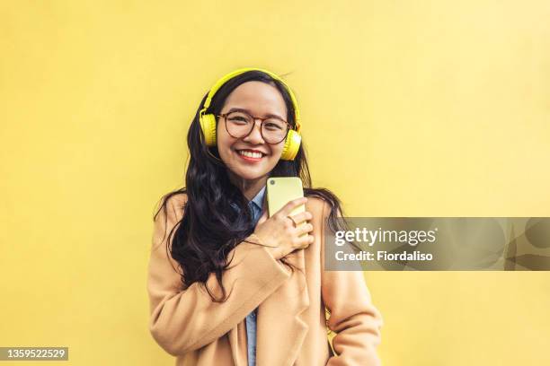 young asian woman with headphones - vrouw spleetje tanden stockfoto's en -beelden