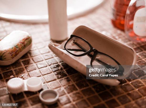 eyeglasses and contacts lenses on bathroom sink - contacts stock-fotos und bilder