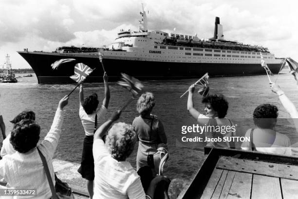 Des femmes brandissent le drapeau britannique lors de l'arrivée à Portsmouth du paquebot anglais Queen Elisabeth II avec des blessés pendant la...